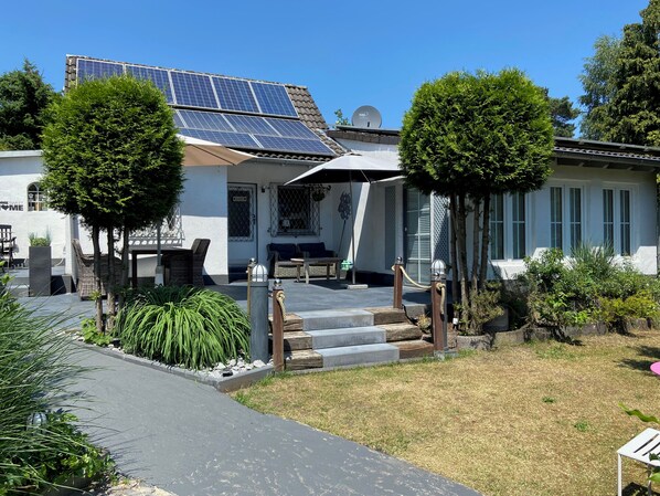 A house with solar panels, a covered patio, and a small garden.