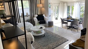 Un salon moderne comprenant un canapé, des fauteuils, une table basse et un coin repas avec des chaises et une table.