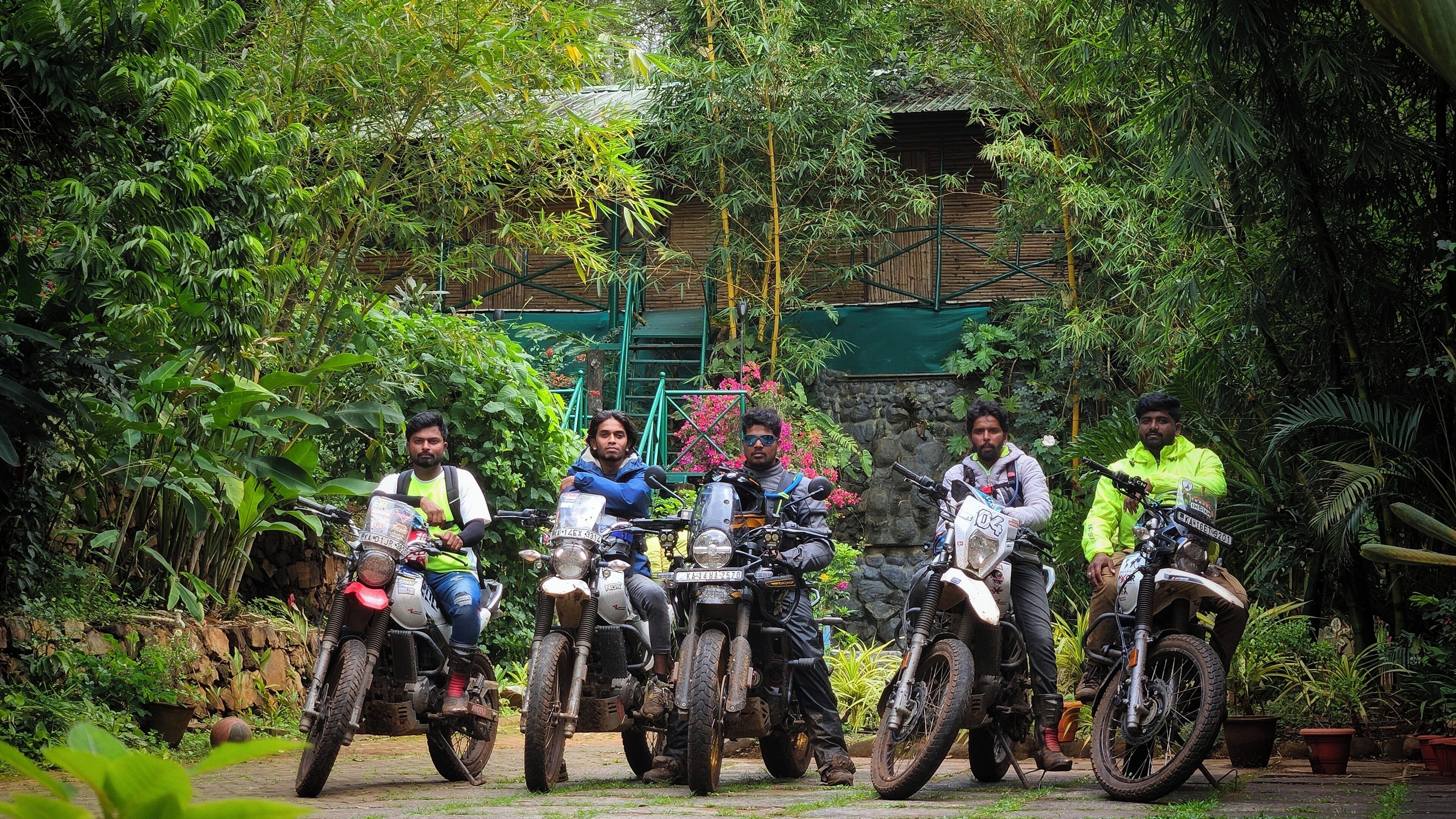 A group of people on motorcycles in a lush, green outdoor setting.