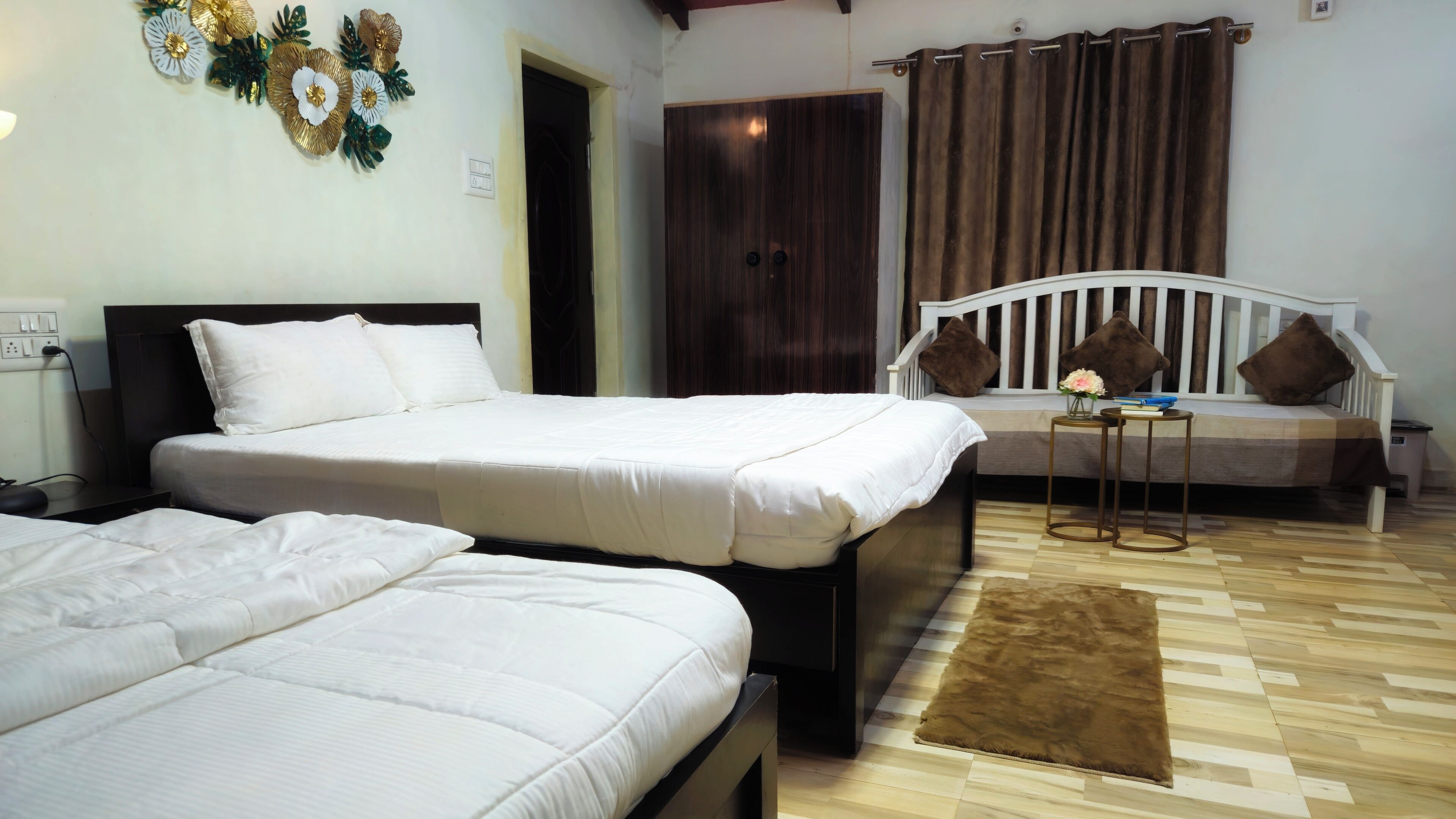 Habitación de hotel con dos camas, un sofá, una mesita y un tapete marrón.