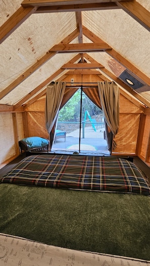 Une tente dotée d’un espace pour dormir, d’une fenêtre et offrant une vue sur l’extérieur.