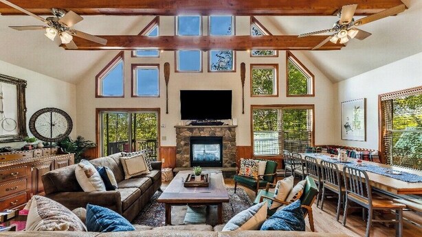 A spacious living area with a fireplace, wooden beams, and large windows.