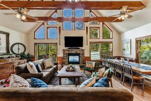 Amplia sala de estar con chimenea, vigas de madera y ventanas grandes.