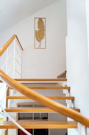 A staircase with wooden handrails and a white wall with a leaf-shaped decoration. - Golden River Apartment (Hlavní mesto Praha)