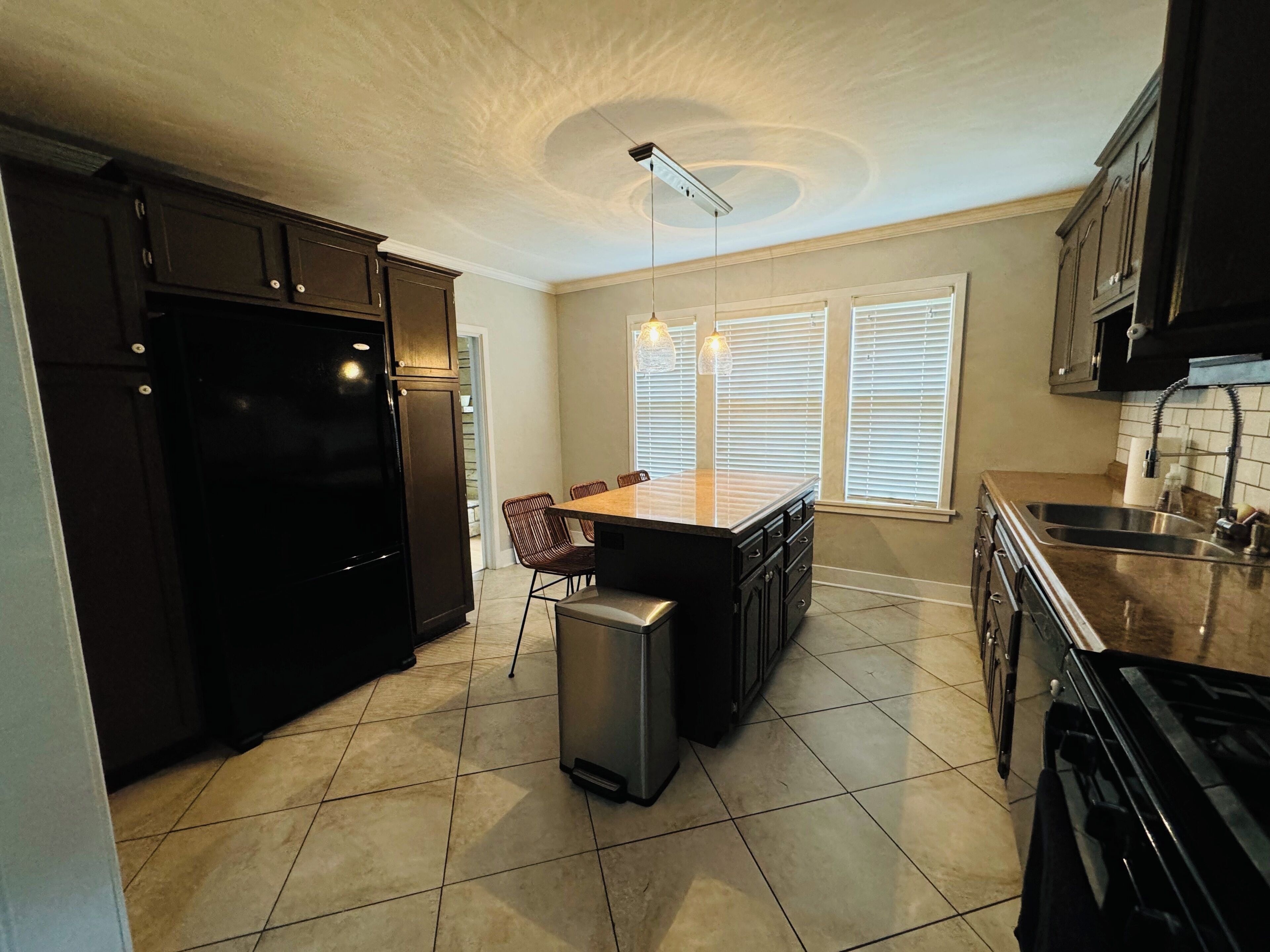 A modern kitchen with dark cabinetry, a central island, and pendant lighting.