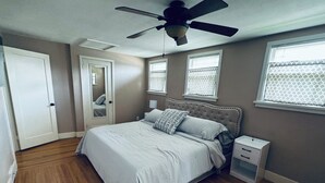 A bedroom with a bed, a nightstand, a ceiling fan, and two windows with blinds. - Charming 3-bedroom house in historic grandview neighborhoods  (Dubuque)