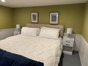 A bedroom with a bed, two bedside tables, and two wall-mounted signs.