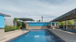 A swimming pool with a blue and white color scheme, surrounded by a covered area with a striped awning.