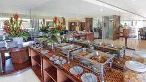 A buffet area with multiple food stations, a reception desk, and a seating area with chairs and tables.