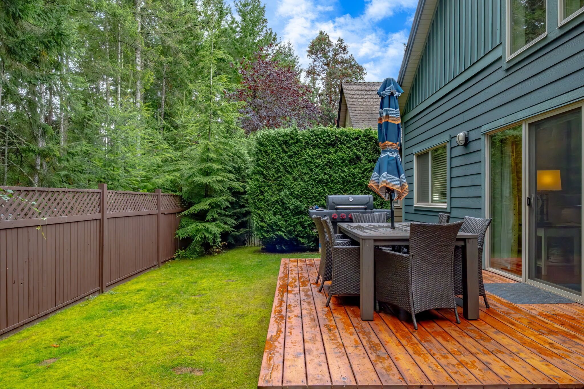 A wooden deck with outdoor furniture, a grill, and a covered patio area.