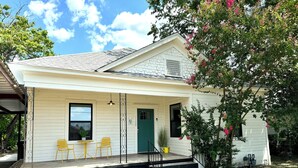 A single-story house with a front porch, two windows, a green door, and a small garden area with a potted plant. - ꕥ The Texas Bluebonnet ꕥ 1.1 mi to Baylor, & 1.8 mi to Magnolia Silos! (Waco)