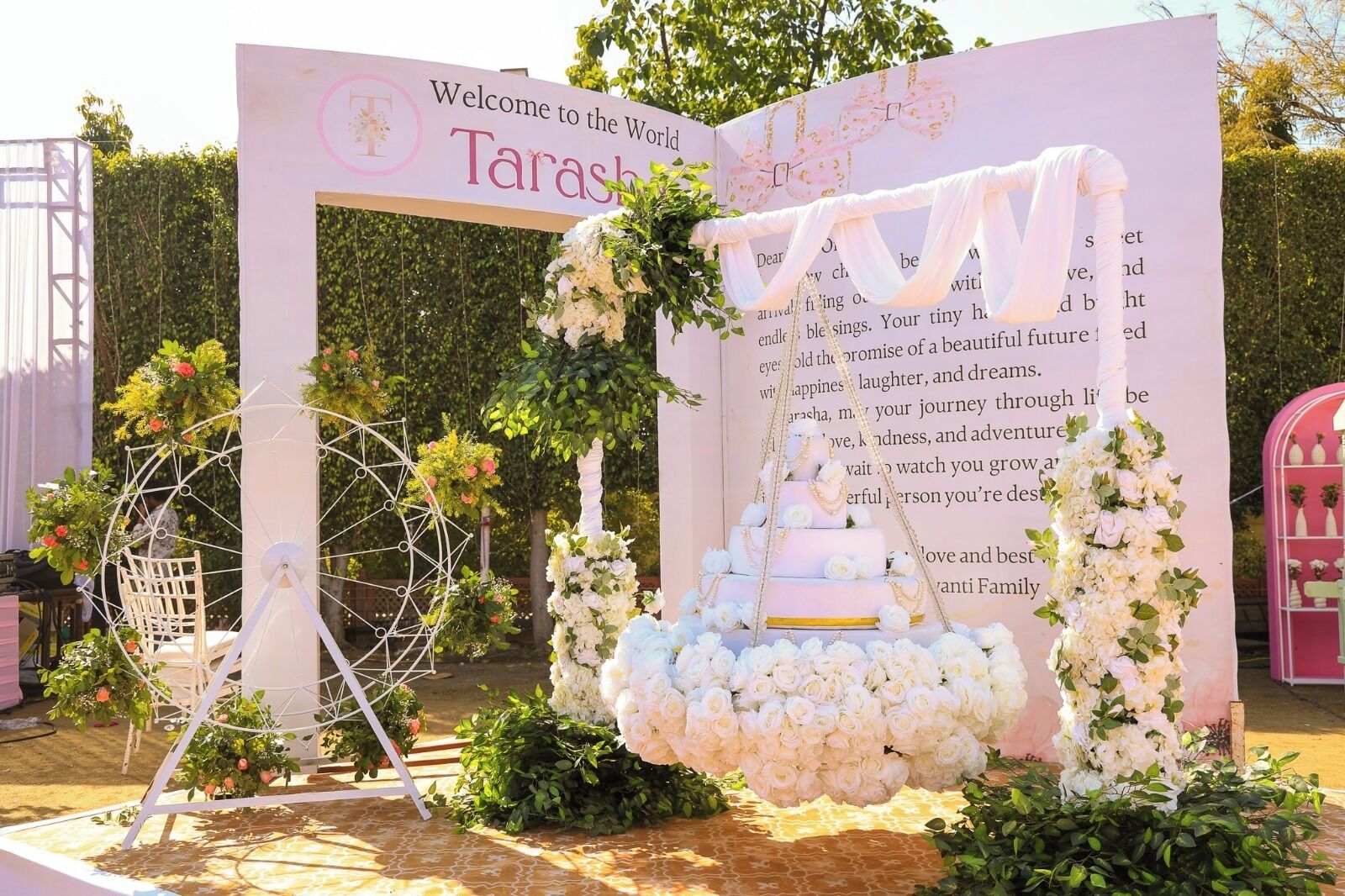 Decoración con una noria, un arreglo floral escalonado y un fondo con un mensaje de bienvenida.
