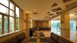 A spacious lobby with a long reception desk, leather seating, and large windows.