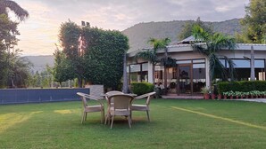 A modern building with a glass entrance, surrounded by lush greenery and a well-maintained lawn.