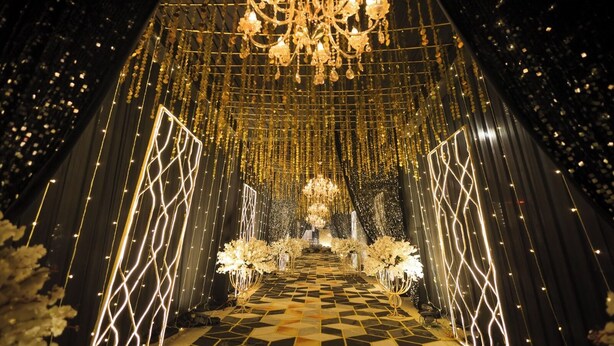 A grand hall with a chandelier, floral arrangements, and a checkered floor.