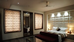 A hotel room with a large bed, a red sofa, a glass coffee table, and a ceiling fan.