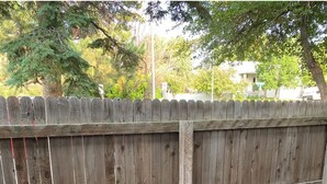 A backyard with a wooden fence, two black folding chairs, and a concrete patio. - Cozy 2-bedroom condo close to both Denver and the Mountains (Denver)