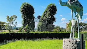 A statue of a bird on a pedestal in a grassy area with a fence and trees in the background. - Hôtel & Events du Château Lacaze (Aiguillon)