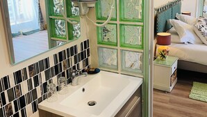 A bathroom with a white sink, a mirror, and a green patterned wall. - Hôtel & Events du Château Lacaze (Aiguillon)