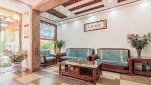 A reception area with a wooden coffee table, two green sofas, and a potted plant.