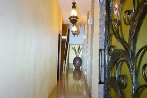 Un pasillo con piso pulido, una reja decorativa y un colgador de luces.