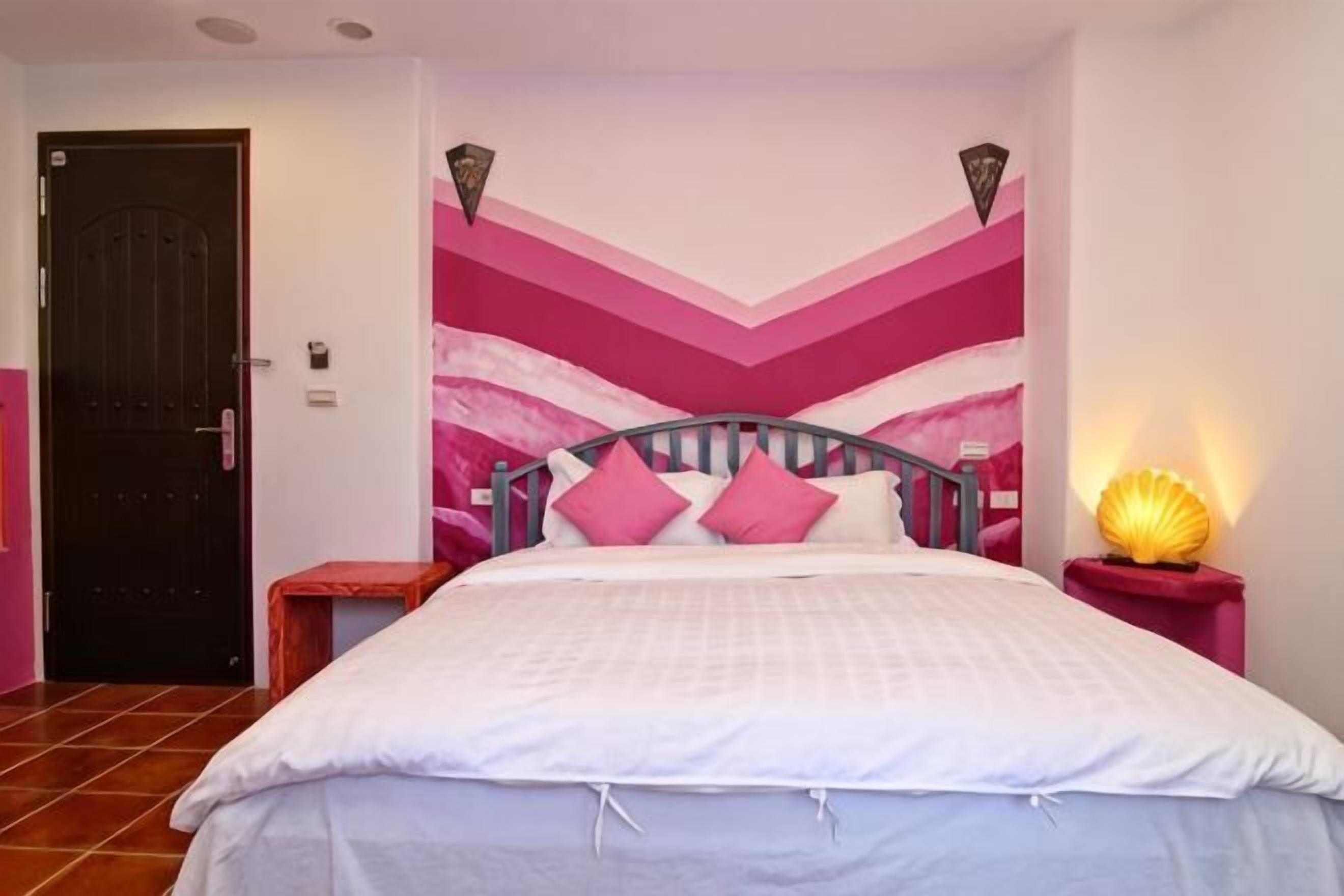 Una camera da letto con un letto, un comodino, una lampada e una porta.