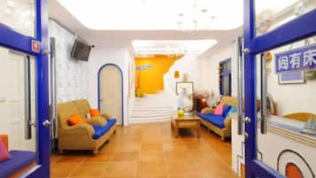 A hotel lobby with a staircase, sofas, and a reception desk.