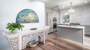 A modern kitchen with a central island, built-in ovens, and a large window. - Elegant Lake Retreat (Mount Dora)