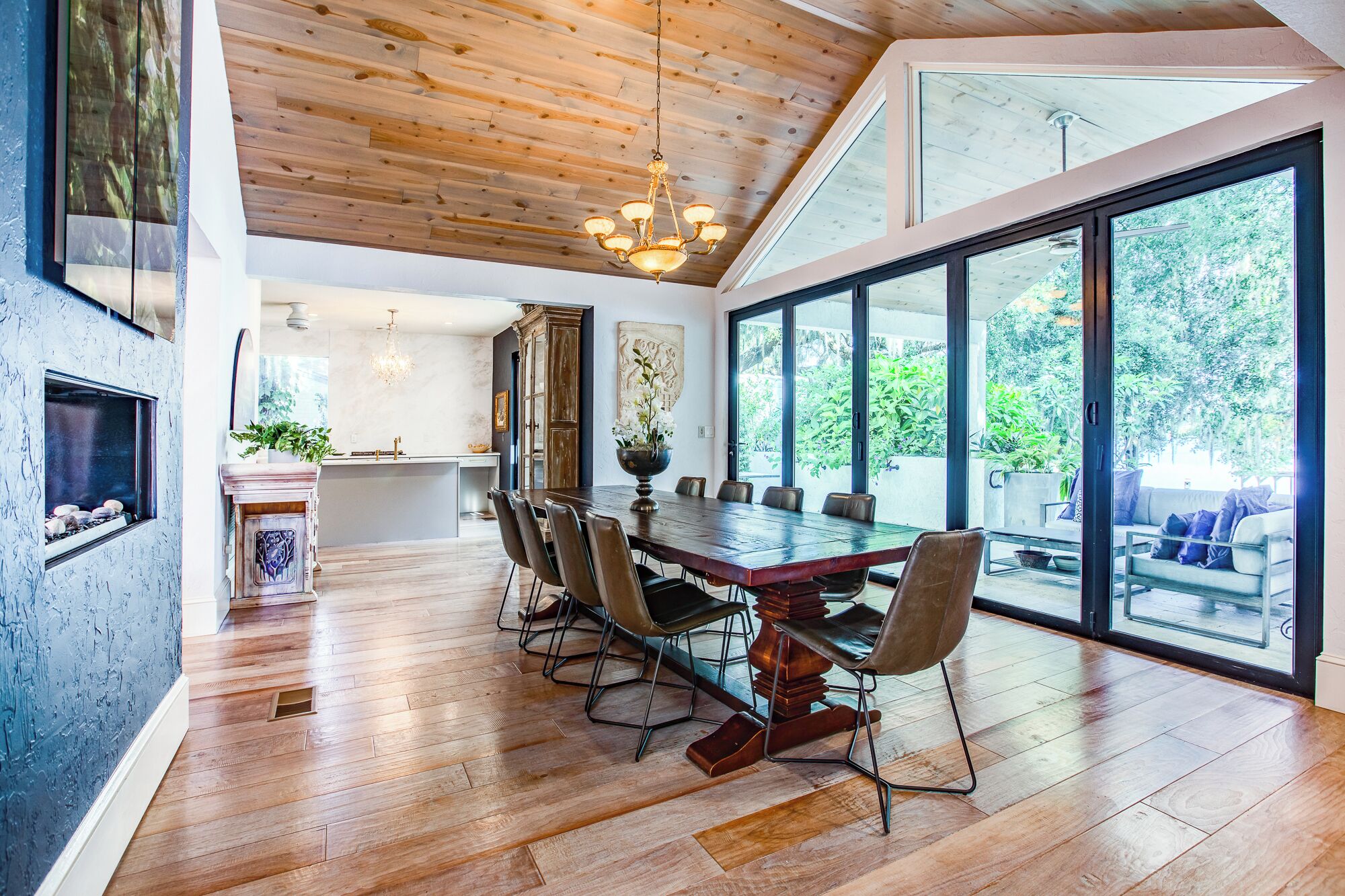 Un comedor amplio con una gran mesa de madera, sillas modernas y vistas al exterior a través de amplios ventanales.