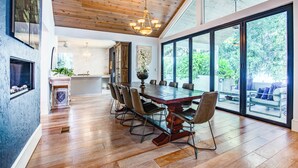 A spacious dining area with a large wooden table, modern chairs, and a view of the outdoors through large windows. - Elegant Lake Retreat (Mount Dora)