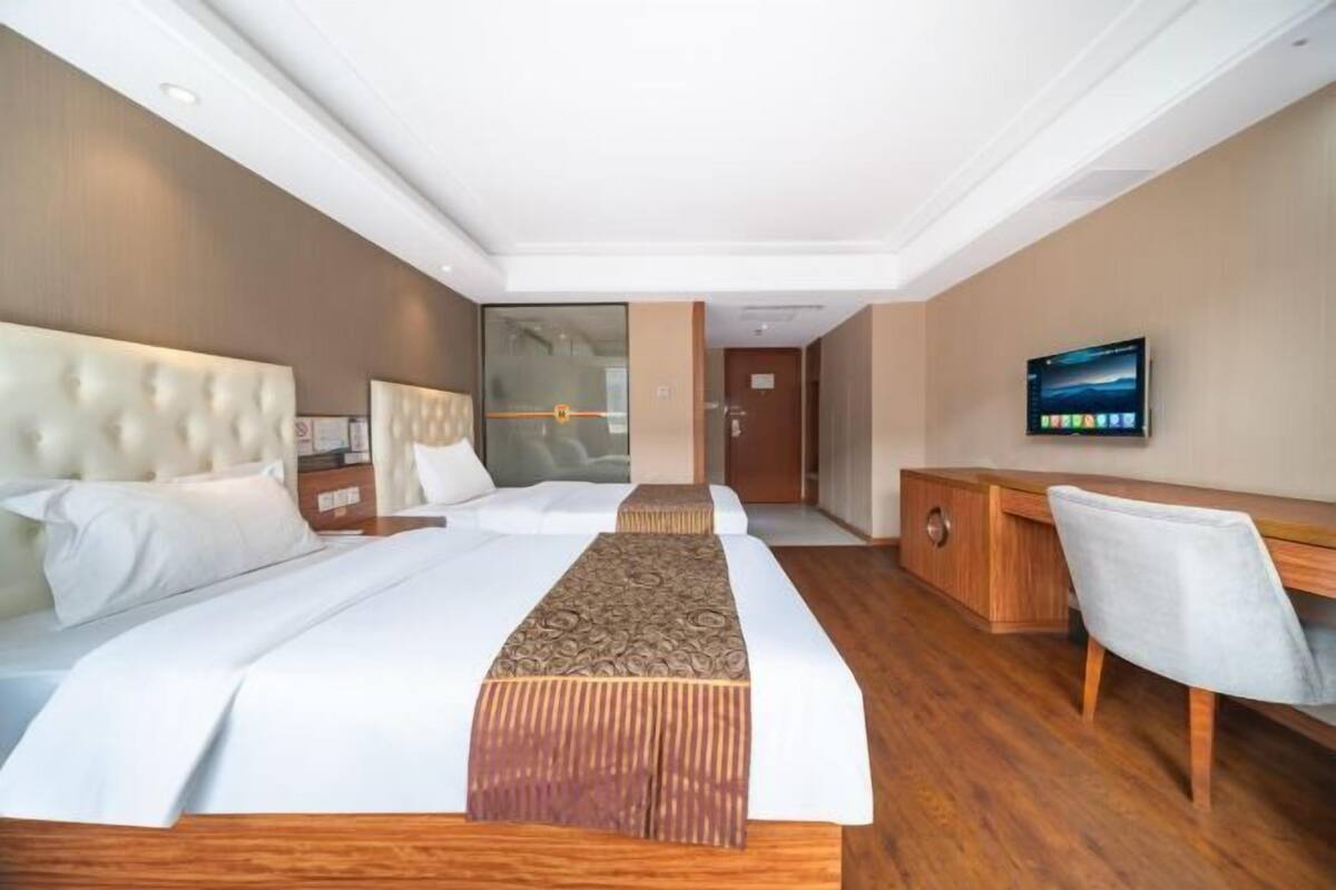 Habitación de hotel con una cama grande, un escritorio, una silla y un televisor en la pared.