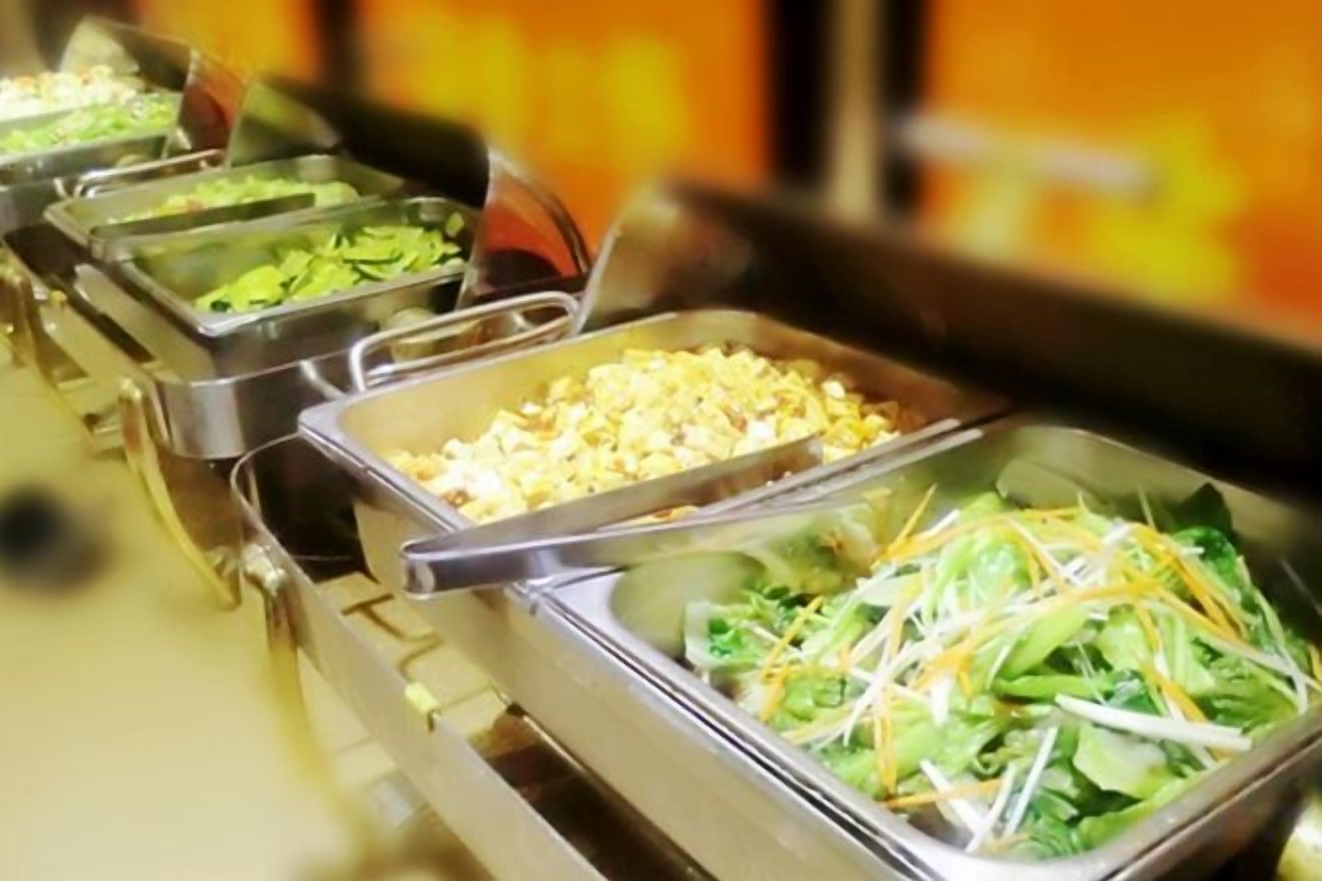 Buffet com diversas opções de comida em bandejas de metal.