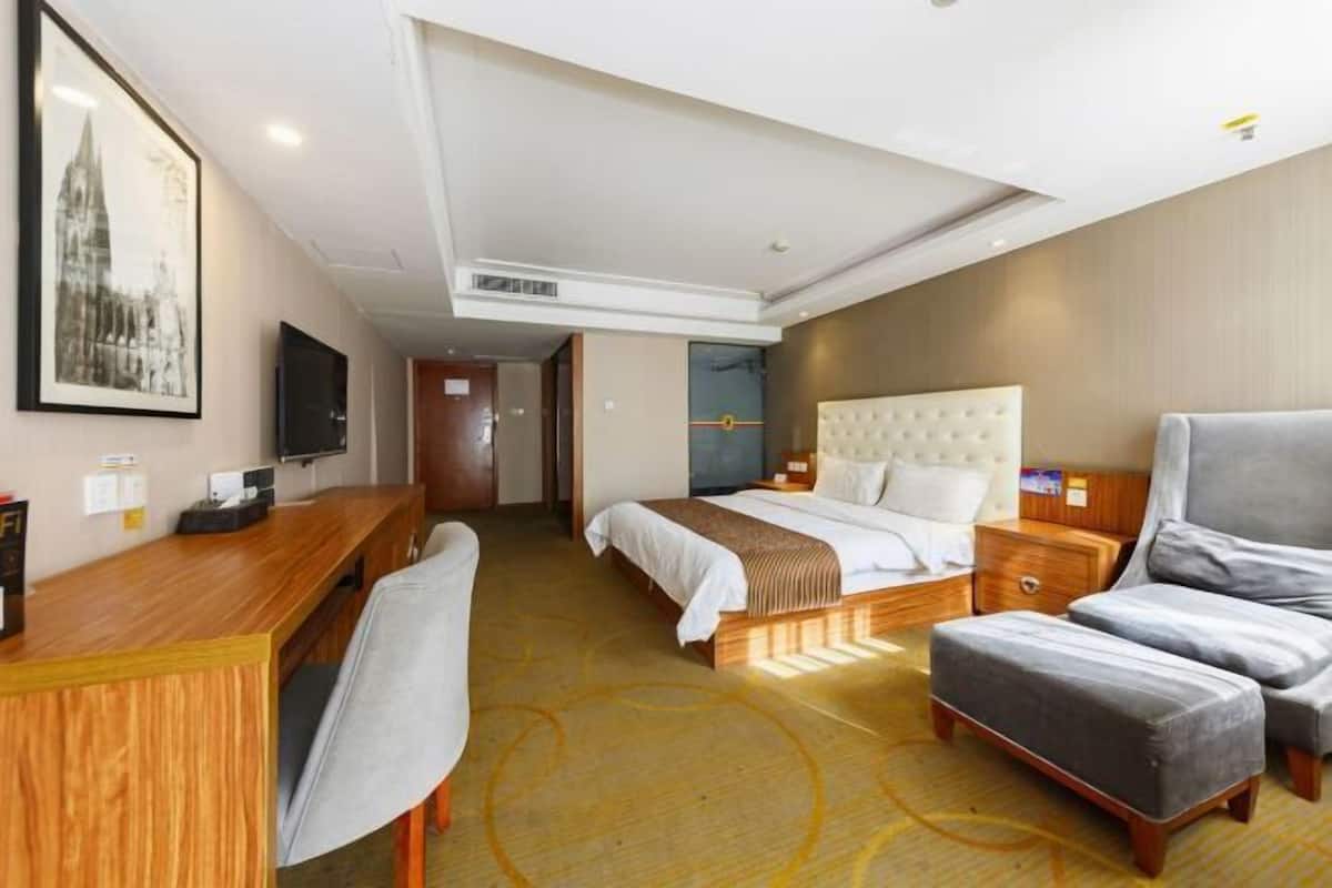 Una habitación de hotel con una cama, un escritorio, una silla y un televisor.