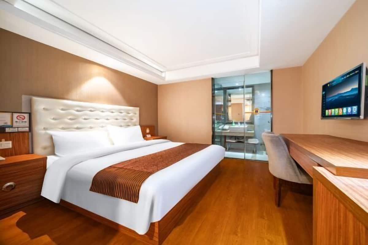 Una habitación de hotel con una cama grande, un escritorio y un televisor.