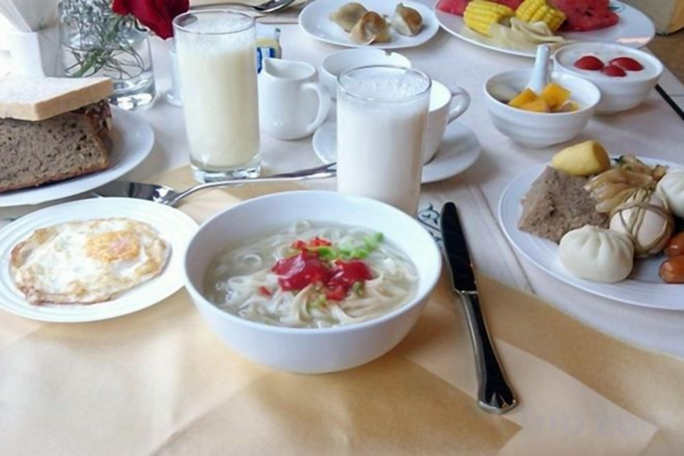 A table with various dishes including a bowl of soup, plates of food, and a glass of milk.