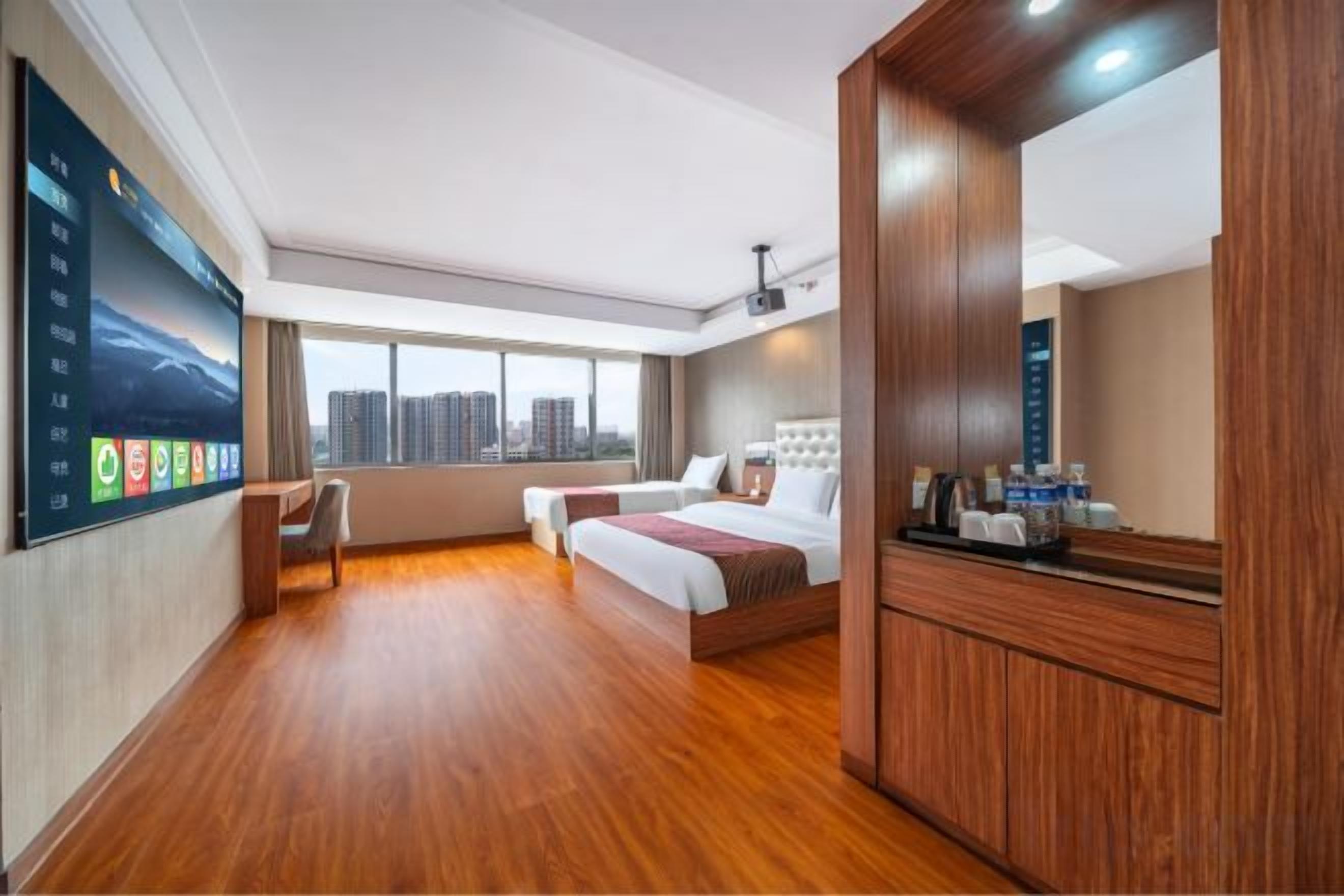 Habitación de hotel con una cama grande, un escritorio, una silla, un televisor y una ventana con vistas a la ciudad.