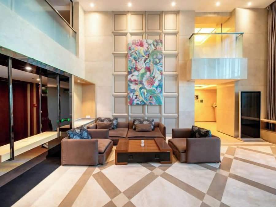 Een moderne lobby met een groot abstract schilderij, een zithoek met banken en een salontafel, en een receptiebalie.
