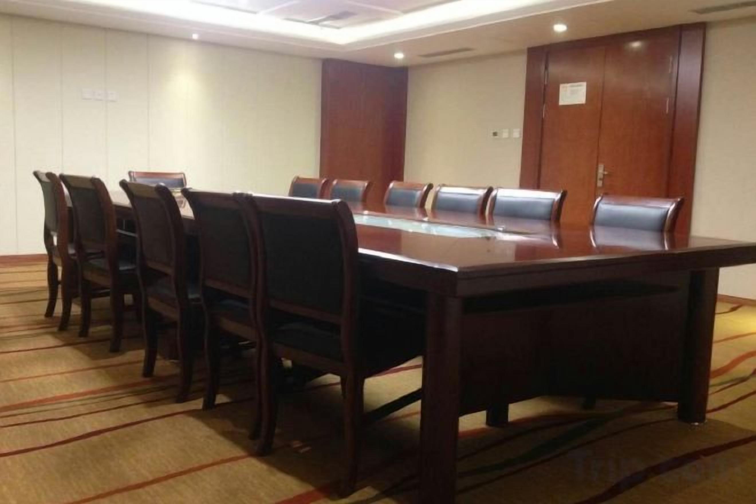 A conference room with a long table and chairs, carpeted floor, and wooden panel walls.