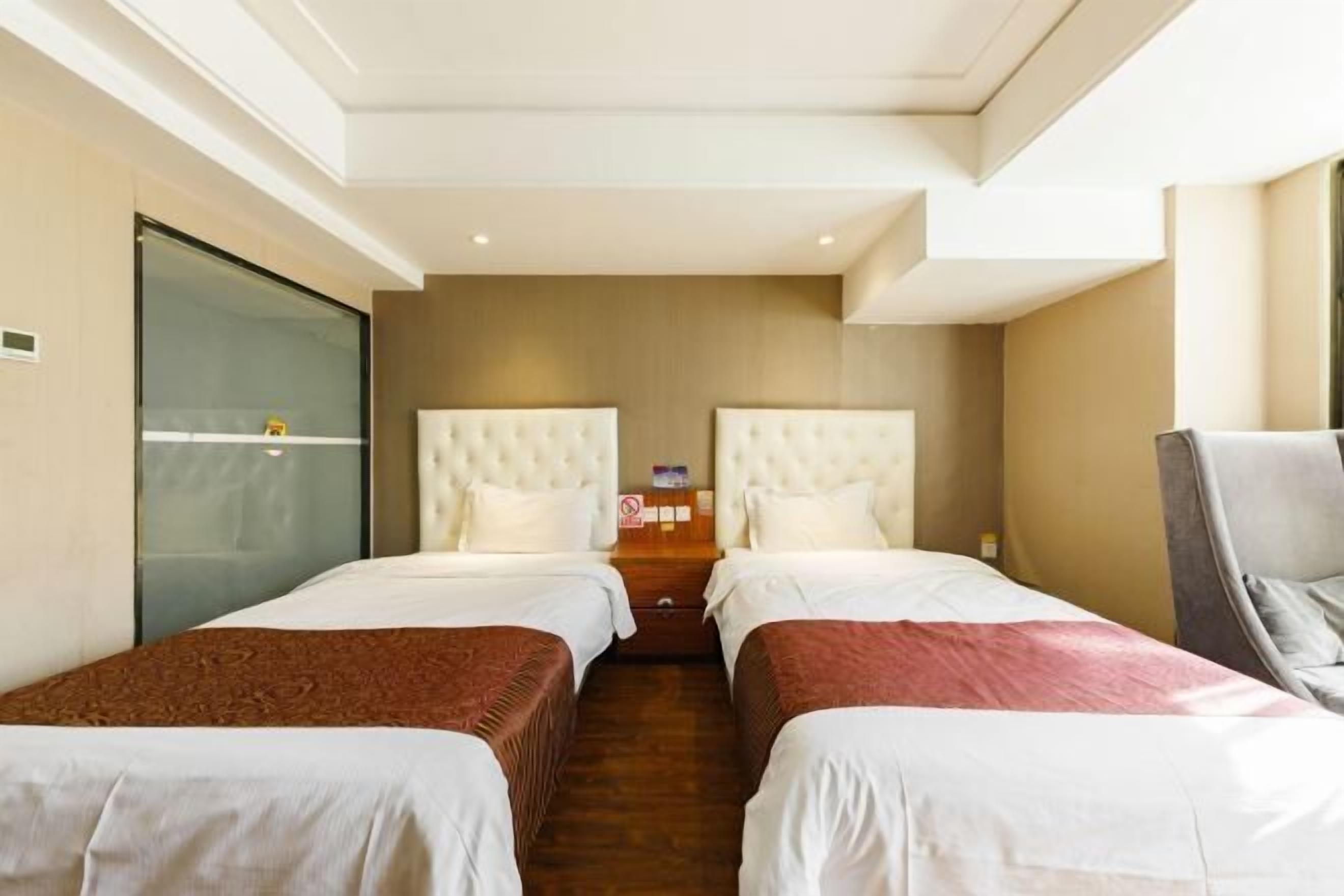 Ein Hotelzimmer mit zwei Betten, einer Glastrennwand und einem Holzboden.