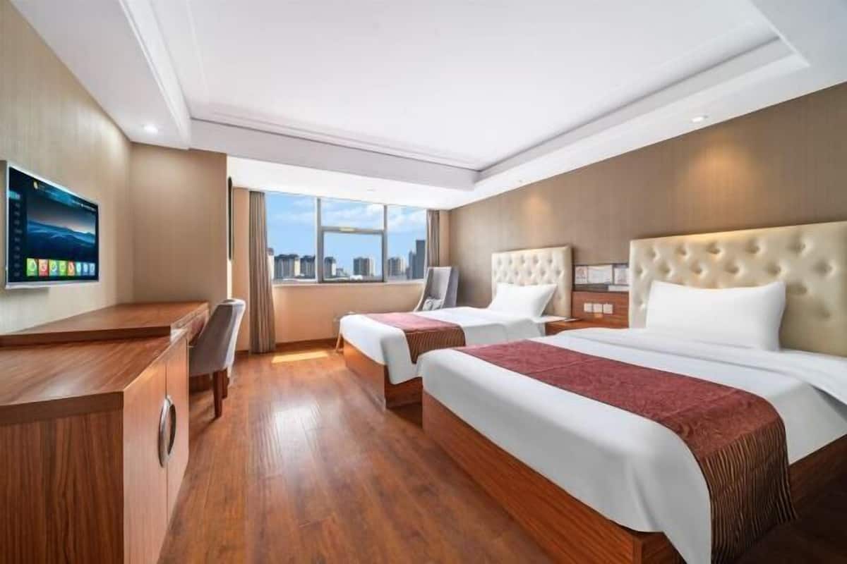 Habitación de hotel con dos camas, un escritorio, un televisor y vistas a la ciudad.
