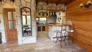 Une cuisine rustique avec des murs en pierre, des poutres en bois et un coin bar avec des chaises.