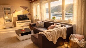 Un salón con sofá, televisión y vista al río.