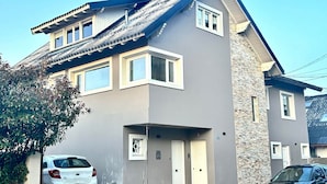 Ein zweistöckiges Gebäude mit einer grauen Fassade, einem Akzentmauer aus Stein und einem geneigten Dach.