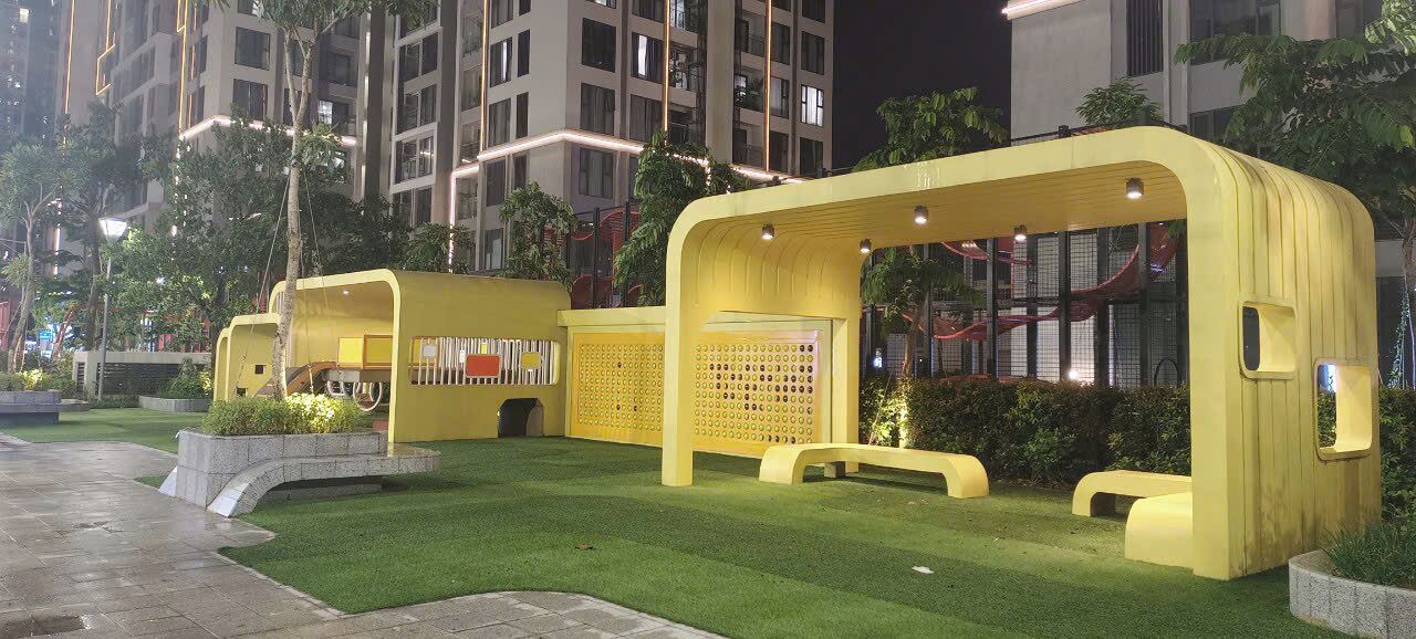 Un espace extérieur aménagé avec des sièges jaunes, un mur décoré de motifs et un petit jardin.