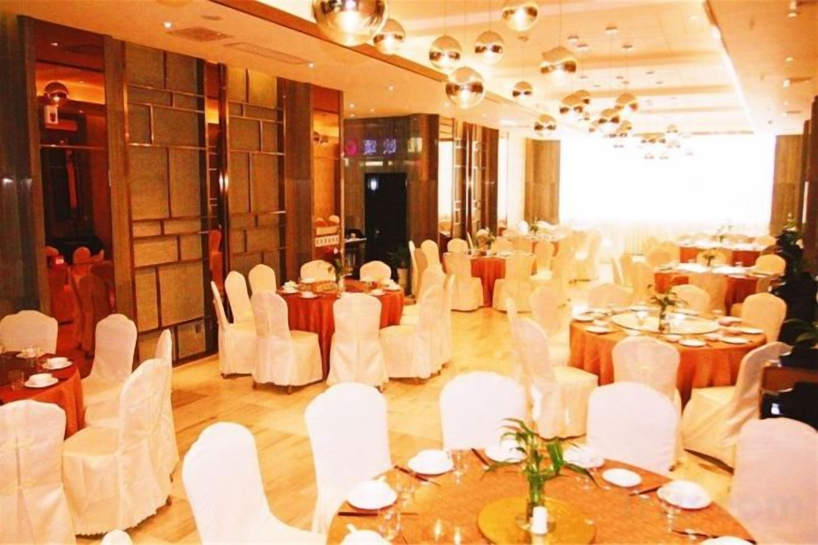 Un salón de banquetes con mesas redondas y sillas, algunas mesas dispuestas para comer.