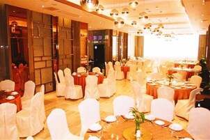Un salón de banquetes con mesas redondas y sillas, algunas mesas dispuestas para comer.