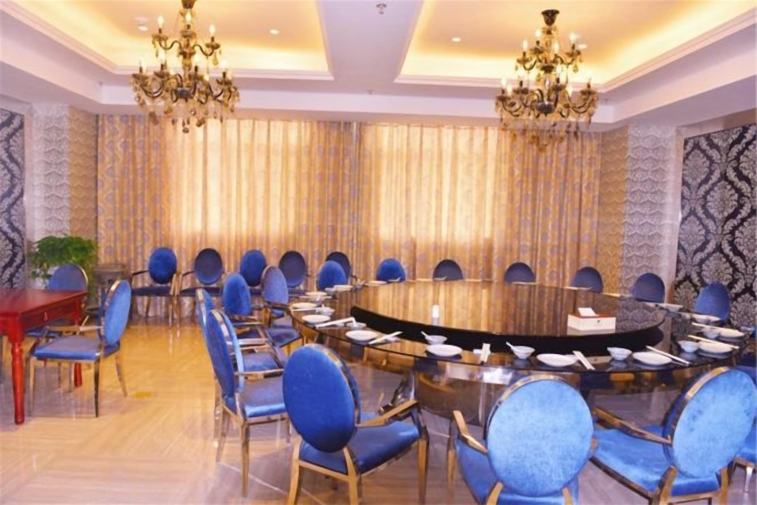 A conference room with a round table, blue chairs, and chandeliers.