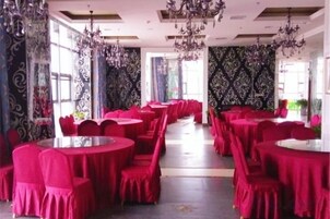 Un salón de banquetes con mesas y sillas redondas, ventanas amplias y candelabros.