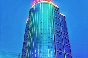 Un edificio alto con fachada de vidrio reflectante y un letrero rojo en la parte superior.