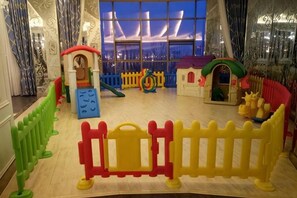 A children's play area with various play structures and a view of the outside through large windows. - Shengda Hotel (Guangshan)